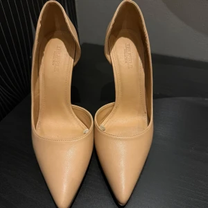 Beige pumps med spetsig tå från Truffle - Snygga beige pumps från Truffle Collection köpte i Asos med spetsig tå och hög klack. Skorna har en stilren design i syntetmaterial och passar perfekt till dig som vill ha en elegant look. Klassisk modell med öppen insida och smal klack.