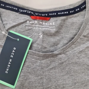 Grå t-shirt från Race Marine - En stilren grå t-shirt från Race Marine med rund halsringning och en liten bröstficka. T-shirten är i mjuk bomull och har en klassisk passform som funkar till allt. Perfekt basic-plagg för garderoben.