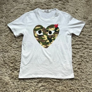 CDG camo t-shirt - Hej🙌, säljer nu min fina, sällsynta och eftertraktade tröja från märket Comme des Garçons perfekt nu till sommaren. T-shirten är i gott sick och är i storlek L men skulle säga att den riktar sig mer åt M hållet. Skriv vid funderingar!