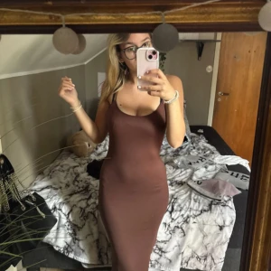 Långklänning  - Säljer en snygg brun långklänning med smala axelband och figurnära passform. Klänningen är ärmlös och har en enkel, stilren design som framhäver siluetten. Perfekt för dig som gillar minimalistisk stil och vill ha något bekvämt men ändå trendigt. Jag är 167cm