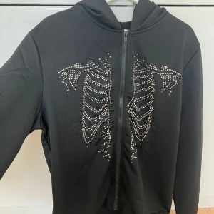 Cool zip hoodie med skelett - Ny och oanvänd svart zip hoodie med stenar i ett skelett mönster fram. 229kr på hemsidan.