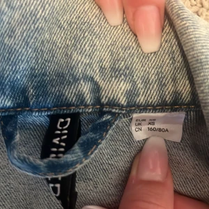Oversized ljusblå jeansjacka Divided XS - Snygg oversized jeansjacka från Divided i ljusblå denim. Klassisk modell med krage, bröstfickor med knappar och långa ärmar. Perfekt att slänga över en hoodie eller t-shirt för en chill look.