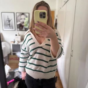 Vit och grön randig tröja H&M - Vit stickad tröja från H&M med gröna ränder och v-ringad hals. Tröjan har trekvartsärm och en avslappnad passform. Så fin och perfekt nu till hösten! 🥰