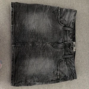 Grå jeanskjol från LTB - Snygg grå jeanskjol från LTB med slitna detaljer och klassisk femficksdesign. Kjolen har bälteshällor, knapp och dragkedja framtill samt coola bakfickor med broderade detaljer. Perfekt för dig som gillar en edgy och avslappnad stil.