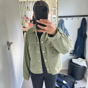 Grön jeansjacka från Zara  - Snygg grön jeansjacka från Zara. Jackan har två stora bröstfickor med knappar, klassisk krage och raka ärmar. Tillverkad i bomull med en loose passform, perfekt till sommarn!
