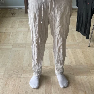 Beiga linnebyxor med snörning - Säljer ett par beiga linnebyxor med avslappnad passform och snörning i midjan. Byxorna är raka i modellen och perfekta för varmare dagar. Lätta och luftiga med klassisk look. Skriv privat för fler bilder.
