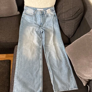 Ljusblå wide jeans från Bershka - Säljer ett par ljusblå jeans från Bershka i storlek 42. Modellen har hög midja och raka, vida ben för en avslappnad och trendig look. Klassisk femficksdesign och tillverkade i jeansmaterial. Perfekta till sneakers eller boots. Aldrig använt 