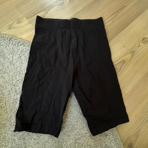 Svarta cykelshorts i bomull - Svarta cykelshorts med elastisk midja och knälång passform. Gjorda i mjuk bomull som är sköna att ha på sig, perfekta för träning eller chill. Enkla och stilrena utan synliga detaljer eller mönster.