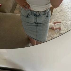 Ljusblå jeanskjol från Gina tricot  - Säljer en ljusblå jeanskjol från Gina Tricot i klassisk femficksmodell. Kjolen är kort, har normal passform och är tillverkad i denim med snygg tvätt. Perfekt till sneakers eller boots för en chill look.
