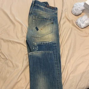 Dondup jeans - Säljer ett par blå Dondup jeans med slitna detaljer och hål på både fram- och baksida. Jeansen har en slim passform, Sitter lite skumt på mig för de är för långa. Storlek 30