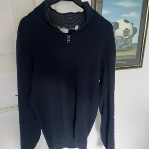 Mörkblå stickad tröja från Esprit - Mörkblå stickad tröja från Esprit med half zip-dragkedja vid halsen. Tröjan är långärmad och har en mjuk känsla tack vare materialblandningen av bomull och kashmir. Perfekt för dig som gillar en stilren och enkel look.