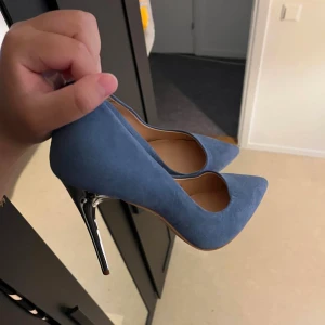 Blå mocka pumps med klack - Säljer ett par stilrena blå pumps i mocka med spetsig tå och hög smal klack. Perfekta för dig som vill sticka ut med färg och elegans. Snygga till både jeans och klänning!