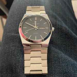 Silverfärgad herrklocka med blå urtavla - Stilren herrklocka från Forsining med blå urtavla och dag/datumvisning. Klockan har ett armband i rostfritt stål och klassisk kvartsrörelse. Passar perfekt för dig som gillar en modern och tidlös look.