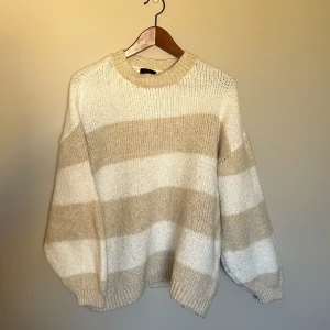 Beige och vit randig stickad tröja från LXA - Mysig stickad tröja från LXA i storlek S. Tröjan har breda beige och vita ränder, rund halsringning och långa ärmar. Sparsamt använd! 