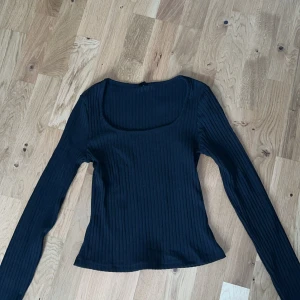 Svart ribbad långärmad topp - Säljer en svart ribbad topp med lång ärm och rundad urringning. Toppen har en tight passform och är perfekt att styla till olika outfits. Storlek s