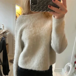 Ljusbeige fluffig stickad tröja - Mysig ljusbeige stickad tröja med fluffig yta och rund halsringning. Tröjan har lång ärm och en något croppad passform. Perfekt för lager-på-lager och enkel att matcha till olika outfits.