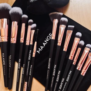 Makeup brush set från MaaNge! - 13 högkvalitativa sminkborstar i olika storlekar med extra mjukt syntethår och skaft i svart och guld från MaaNge. En svart förvaringspåse i sammet med dragsko och två trekantiga beautypuffs med praktiska fingerfästen för enklare applicering medföljer. Nytt och oanvänt.