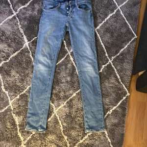 Ljusblå skinny jeans från Dondup - Säljer ett par ljusblå skinny jeans från Dondup med klassisk femficksdesign och knappar i gylfen. Jeansen har en smal passform och är perfekta för dig som gillar en tajt stil. Snygga att matcha med både t-shirt och hoodie. Skicket är 8/10 och nypris är 3000:-