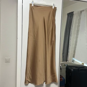 Beige satinkjol - nyskick - Säljer min beige långkjol i satin. Den är i storlek S. Nyskick. Superbekväm. Färgen är mellan beige och ”koppar” så den är lite glansig.