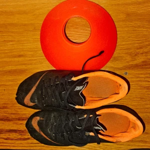 Svarta och orangea Nike fotbollsskor - Säljer ett par svarta Nike fotbollsskor med orangea detaljer och innersida. Skorna har snörning och är designade för att ge bra grepp på planen. Perfekta för dig som vill sticka ut med snygg stil på matchen.