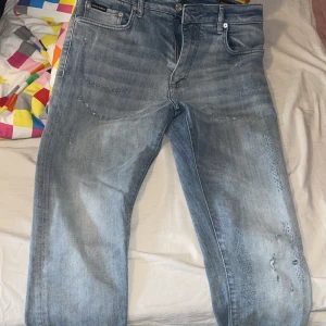 Ljusblå jeans från Dolce & Gabbana - Säljer ett par ljusblå jeans från Dolce & Gabbana med klassisk femficksdesign och metallmärke bak. Jeansen har dragkedja och knapp i midjan samt diskreta slitningar framtill för en trendig look. 