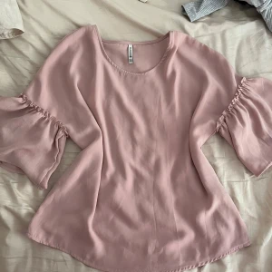 Ljusrosa blus med volangärmar  - Säljer en ljusrosa blus från stradivarius med vida volangärmar. Blusen har en lös passform och är tillverkad i ett mjukt, lätt material som ger ett luftigt intryck.