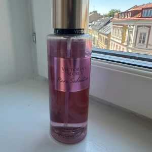 Victoria's Secret Pure Seduction Body Mist - En lyxig body mist från Victoria's Secret i doften Pure Seduction. Flaskan är rosa med guldigt lock och rymmer 250 ml. Doften har inslag av plommon och fresia, perfekt för dig som gillar fruktiga och blommiga toner. Använd lite.
