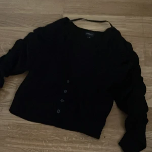 Svart kofta från Lindex - Säljer en svart kofta från Lindex i storlek S. Koftan har långa ärmar och knappar framtill. Perfekt att slänga över en topp eller klänning för en enkel och stilren look. 
