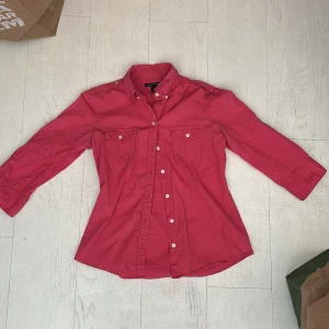 Rosa skjorta med knappar - Säljer en snygg rosa skjorta med långa ärmar och vita knappar framtill. 