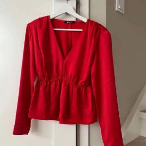Röd blus  - Jättefin röd blus från Gina Tricot med v-ringning och elastisk midja. Knappt använd så i mycket bra skick.