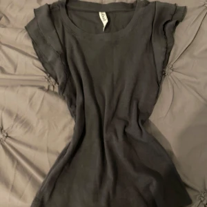 Svart ribbad t-shirt från pageone - En svart ribbad t-shirt från pageone med korta ärmar och rund halsringning. T-shirten har en tight passform och råa kanter vid ärmslut och hals. Perfekt för en enkel och stilren look.