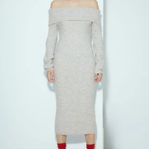 Beige stickad offshoulder långklänning - Superfin beige stickad långklänning med offshoulder och långa ärmar. Klänningen har en ribbad struktur och sitter snyggt med en slim passform. Perfekt för dig som gillar stilrena och mysiga plagg med en modern touch. ENDAST ANVÄND EN KVÄLL.🩷