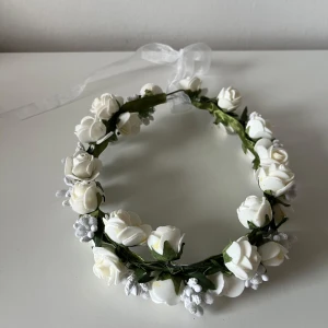 Vit blomsterkrans - Superfin blomsterkrans med vita rosor och gröna blad, dekorerad med små vita bär och ett transparent band för att knyta baktill.