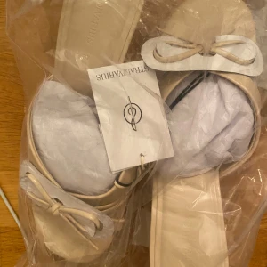 Beige sandaler med rosett från Stradivarius - Snygga beige sandaler från Stradivarius i storlek 37. De har en platt sula och en söt rosettdetalj framtill. Helt nya!! Pris kan alltid diskuteras vid snabb affär!💕