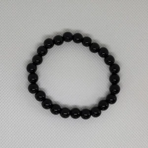 Svart pärlarmband med rundade pärlor - Stilrent svart armband med glansiga, rundade pärlor som sitter på en elastisk tråd. Perfekt för dig som gillar minimalistiska accessoarer med en cool vibe. Passar både ensam eller i kombination med andra smycken för en personlig look.