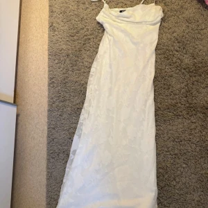 Vit långklänning från Gina Tricot - Supersnygg vit långklänning från Gina Tricot med tunna axelband och subtilt blommönster i tyget.  Storlek S