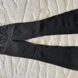 Svarta bootcut jeans från Vero Moda - Svarta jeans från Vero Moda med klassisk femficksdesign och bootcut-ben. Byxorna har hög midja och är tillverkade i ett stretchigt jeanstyg som sitter snyggt. Perfekta till sneakers eller boots för en clean look. Storlek Xxs/32. Nästan aldrig använt 