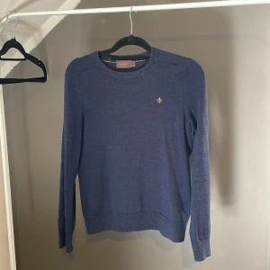 Marinblå merinoulltröja från Morris - Snygg marinblå tröja från Morris i 100% merinoull. Klassisk rund hals och långärmad modell med diskret Morris-logga broderad på bröstet. Helt i nyskick.