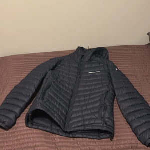 mörkblå dunjacka Peak Performance L - Säljer en svart dunjacka från Peak Performance i storlek L. Jackan har huva, dragkedja framtill och diskret logga på bröstet. I ett bra skick! skulle säga lite lite liten i storlek. 