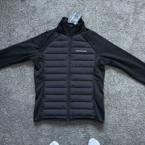 Helt ny Svart dunjacka/cardigan Peak Performance M - Helt ny Svart dunjacka från Peak Performance med quiltad framsida och släta ärmar. Jackan har dragkedja hela vägen, hög krage och diskret logga på bröstet. Perfekt för kyliga dagar och riktigt snygg passform. Priset går att diskuteras, kom gärna med byten. Nypris 2400
