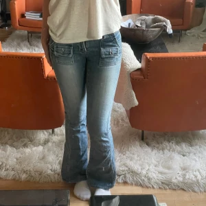 Blå bootcut jeans med fickdetaljer - Säljer ett par jättesnygga lågmidjade bootcut jeans med coola fickor framtill och bak💕Ger en snygg figur och i mycket bra skick! Använda fåtals gånger. Jeansen har en ljus tvätt och markerade sömmar🩷Midjemått: 38 cm Längd: 100 cm. Jag är 172!