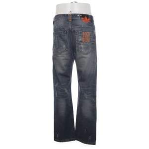 Adidas x Diesel blå jeans med orangea detaljer - Snygga blå, baggy Adidas x Diesel jeans med orange detaljer och broderad logga baktill. Hittar ingen storlek på de men skulle säga att de passar till båda kön. Skulle tippa på att de inte är äkta men oavsett sjukt coola. 