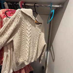 Beige stickad tröja från Gina Tricot - Supermysig beige stickad tröja från Gina Tricot med kabelstickat mönster och stor krage. Perfekt för lager på lager och chill höst- och vinterdagar. Långärmad och i mjukt material som håller dig varm.