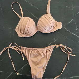 Beige bikini med snörning från Calzedonia - Supersnygg beige bikini från Calzedonia. Bikinin är aldrig använd, inte ens testad. Dessvärre packades den med till Cypern i hopp om att användas så har inga lappar kvar, därav priset 🩷Storlek XS i trosorna, 34 i topp. Justerbar efter önskad storlek! Nypris för båda 918:-