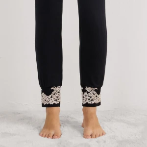 Svarta pyjamasbyxor med spetsdetalj  - Svarta pyjamasbyxor med snygga beige spetsdetaljer längst ner vid bensluten. Byxorna har en slim passform och är perfekta för chill dagar hemma. Tillverkade i mjukt material som känns skönt mot huden. Använt 1-2 ggr💕
