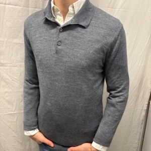 Grå rugbytröja från Riley - Snygg grå rugbytröja från Riley med krage och knappar framtill. Perfekt för en stilren look. Tröjan har långa ärmar och är tillverkad i ett mjukt material som ger en bekväm passform. Hål som har blivit lagat, annars bra skick. Modellen är 182cm/67kg
