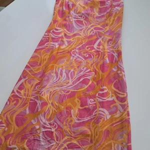 Färgglad långklänning från Episode - Säljer en färgglad långklänning från Episode med ett livligt mönster i rosa, orange och lila. Klänningen är tillverkad i 100% silke och har en elegant passform. Perfekt för somriga tillfällen! Står 38, men 36 i verkligheten.  (Mindre i storleken) 🌸