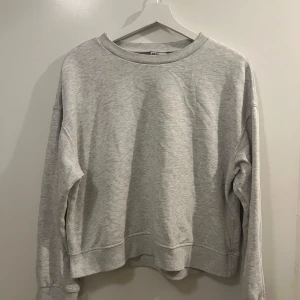 Grå sweatshirt från H&M Divided - Säljer en klassisk grå sweatshirt från H&M Divided. Tröjan har en rund halsringning och långa ärmar. Tillverkad i mjukt material och passar bra till jeans eller leggings.