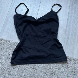 Svart linnetopp från Gina Tricot - Säljer en stilren svart linnetopp från Gina Tricot. Toppen har smala axelband och en enkel design som passar perfekt till olika outfits. Perfekt basplagg för garderoben!