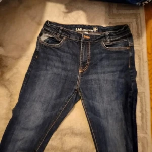 Mörkblå jeans från LAB Industries - Snygga mörkblå jeans från LAB Industries med klassisk femficksdesign och kontrastsömmar. Perfekta för en avslappnad stil. De har en knappgylf och är tillverkade i ett slitstarkt denimtyg.